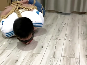 Young Asian man tied up and trying to free himself.